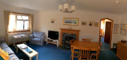 een woonkamer met een tafel en een open haard bij Dalkell Cottage in Tyndrum