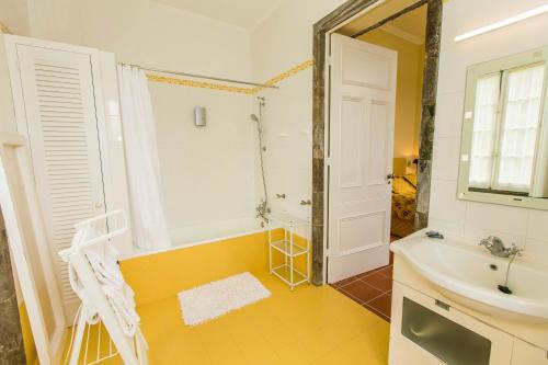 La salle de bains est pourvue d'une baignoire, d'un lavabo et d'un miroir. dans l'établissement Casa Dos Barcos Furnas, à Furnas
