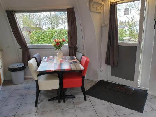 a dining room table with chairs and a vase of flowers at Iglo Bungalow 35 in Chaam