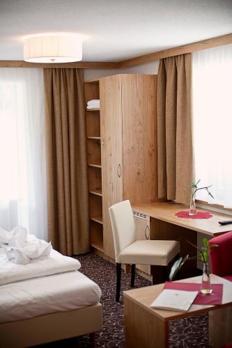 a hotel room with a desk and a bed and a chair at Hotel Erika in Nauders