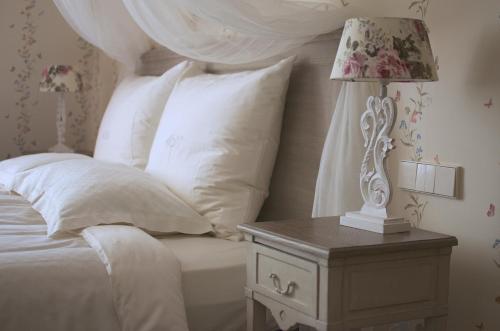 a bed with a table with a lamp on it at Liepupe Manor in Liepupe