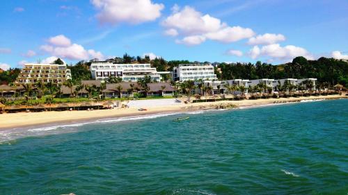 a beach with some buildings and a boat in the water at The Cliff Resort & Residences in Mui Ne
