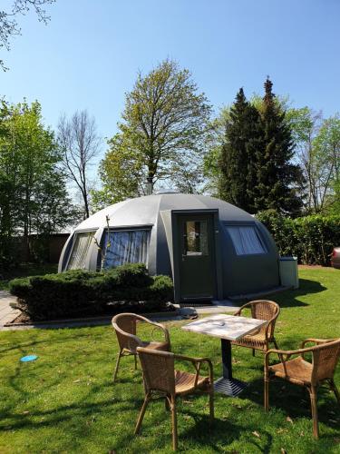 a tent in a yard with two chairs and a table at Iglo Bungalow 35 in Chaam