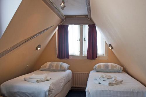 2 camas en una habitación pequeña con ventana en Hotel Torenzicht, en Ámsterdam