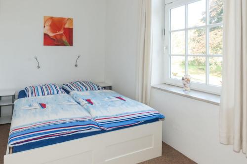 Bett in einem weißen Zimmer mit Fenster in der Unterkunft Ferienhof Kolauerhof - Bauernhofurlaub in Grömitz in Grömitz