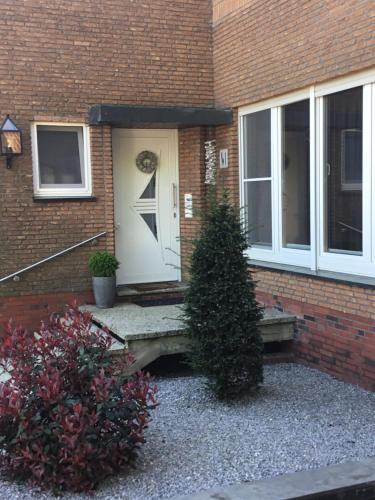 a front door of a brick house with a bush at Ferienwohnung Lands Huys in Dersum