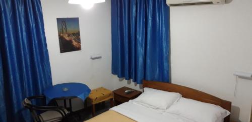 a small room with a bed and blue curtains at San Georgio Hotel in Tsoútsouros