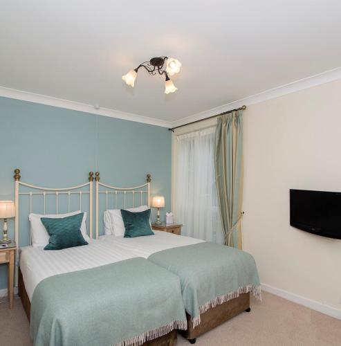 a bedroom with two beds and a flat screen tv at Three Ways House Hotel in Chipping Campden