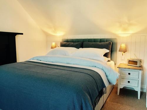 a bedroom with a large bed with a blue blanket at Dandaleith Cottage No.1 in Craigellachie