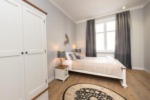 a white bedroom with a bed and a window at Lux Apartment at Planty Park p4you pl in Krakow
