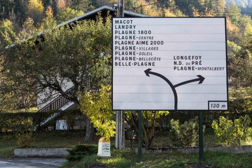 a sign in front of a house with a tree at Maison Lennox in Mâcot La Plagne