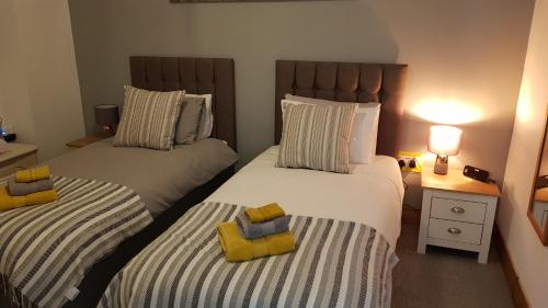2 camas individuales en un dormitorio con 2 lámparas en una mesa en Nant Apartment - Ground Floor en Menai Bridge