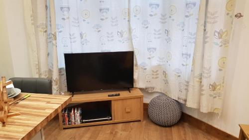 a flat screen tv sitting on top of a wooden table at Nant Apartment - Ground Floor in Menai Bridge