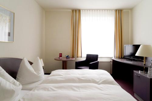 a hotel room with a white bed and a chair at Hotel Erfurter Tor in Sömmerda