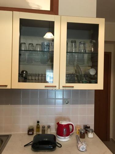 a kitchen with white cabinets and a red appliance at Pinpoint Rooms in Mesolongion