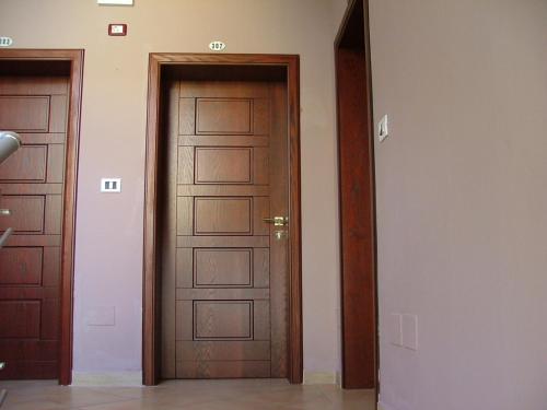 two wooden doors in a room with a hallway at Hotel Dollari in Durrës