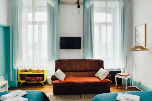 uma sala de estar com um sofá e duas janelas em C&O Guest House Lisbon em Lisboa