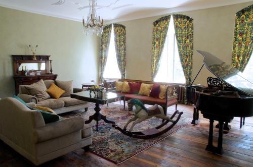 a living room with a couch and a piano at Liepupe Manor in Liepupe