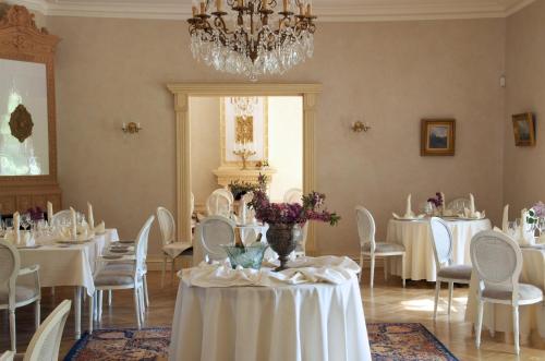 a dining room with white tables and chairs and a chandelier at Liepupe Manor in Liepupe