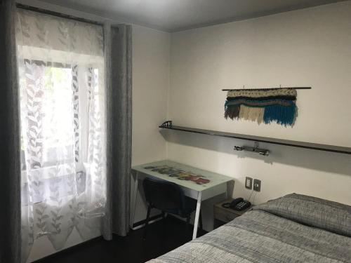 1 dormitorio con cama, escritorio y ventana en Hotel Aysen Austral, en Puerto Aysén
