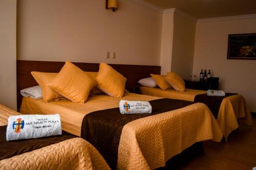 a room with three beds with towels on them at Hotel San Ignacio Plaza in Tunja