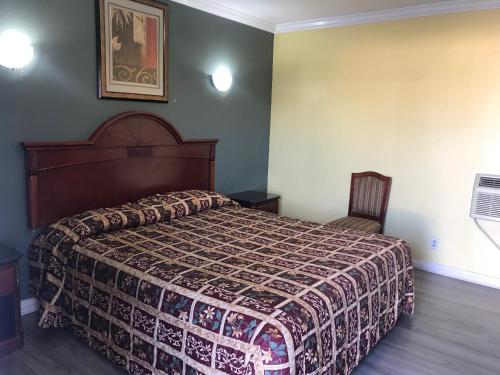 a bedroom with a large bed and a chair at Colony Inn Motel in Bellflower