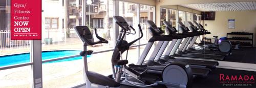 un gimnasio con una fila de cintas de correr junto a una piscina en Ramada Hotel & Suites by Wyndham Cabramatta en Cabramatta