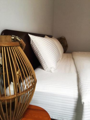 a white bed with white pillows and a basket on a table at Mooning the Hill in Manzhou