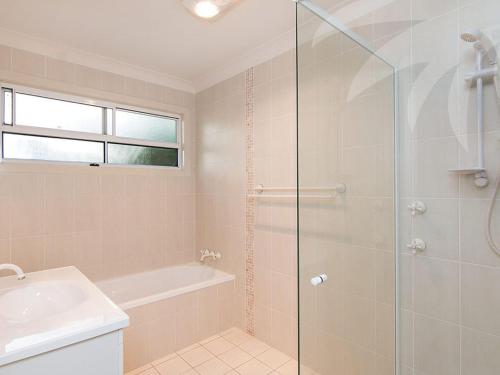 a bathroom with a shower and a tub and a sink at Dunes in Blueys Beach