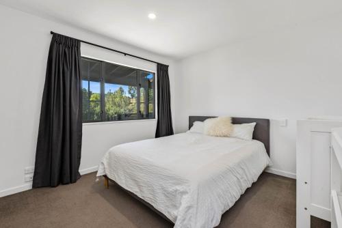 - une chambre blanche avec un lit et une fenêtre dans l'établissement Time Out at Lake Wanaka, à Wanaka