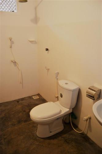 a bathroom with a toilet and a sink at Shim Beach Resort in Arugam Bay