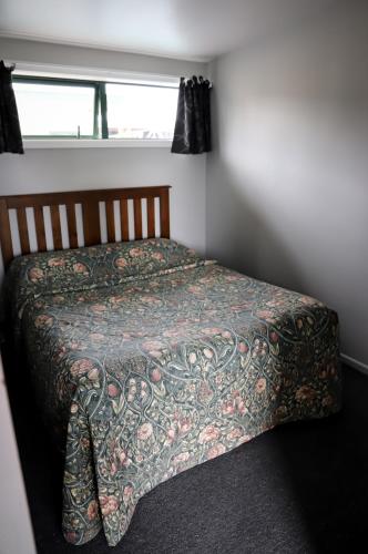a bed in a bedroom with a blanket on it at Coronation Park Holiday Park in Ashburton