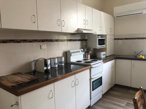 a kitchen with white cabinets and white appliances at Olive's Cottage in Mount Gambier
