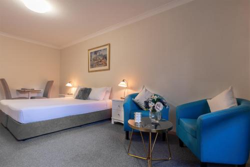 
a hotel room with a bed and a chair at Benson Court Motel in Brisbane
