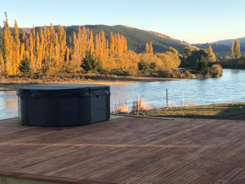 a large black container sitting on a deck next to a river at Mata-au Lodge in Beaumont