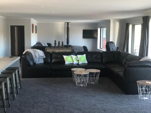 a living room with a black leather couch and tables at Mata-au Lodge in Beaumont