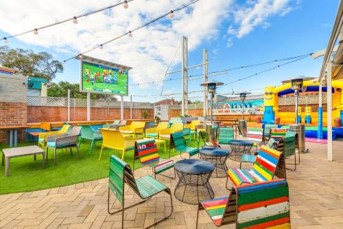 a patio with colorful chairs and tables on a playground at Nightcap at Ocean Beach Hotel in Umina