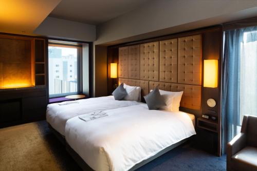 a bedroom with a large white bed with a window at The Royal Park Canvas - Ginza 8 in Tokyo