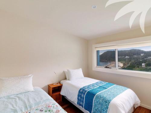 a bedroom with two beds and a large window at Cair Paravel at Seal Rocks in Seal Rocks