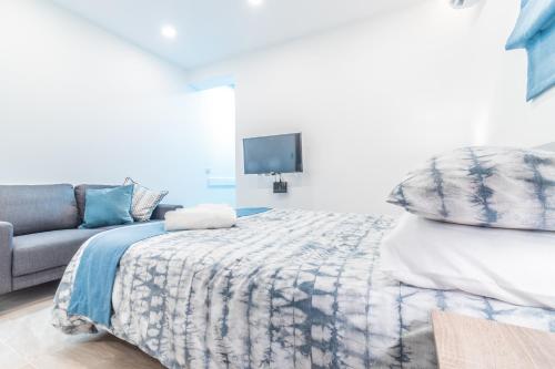 a bedroom with a bed and a couch and a tv at Valletta Collection - GB Suites in Valletta