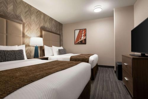 a hotel room with two beds and a flat screen tv at Canalta Airdrie in Airdrie