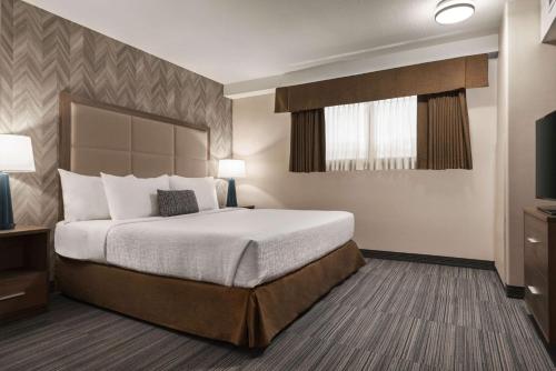 a hotel room with a bed and a television at Canalta Airdrie in Airdrie