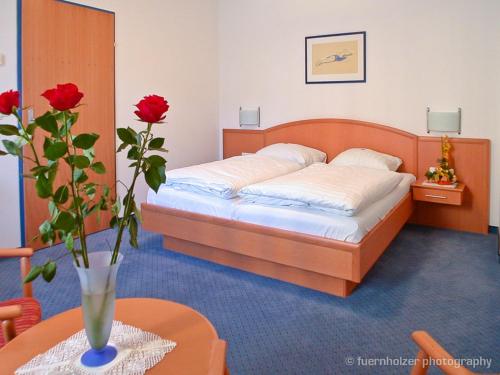 a bedroom with a bed with a vase with red roses at Gasthof Hensle in Sankt Gallen