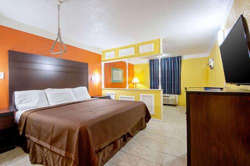 a hotel room with a bed and a flat screen tv at Economy Inn & Suites in Denton