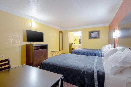 a hotel room with two beds and a flat screen tv at Economy Inn & Suites in Denton