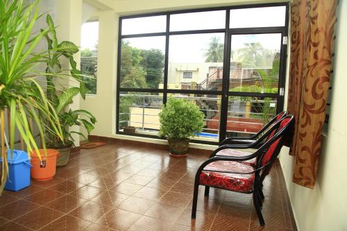 um quarto com plantas e uma cadeira em frente a uma janela em Jai Palace em Chennai