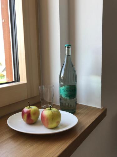 two apples sitting on a plate next to a bottle at Kallido in Hermeskeil