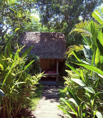 a small hut with a thatched roof in the jungle at Mango Moon in Pemuteran