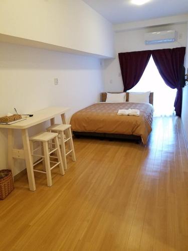 a bedroom with a bed and a table and a desk at M´s Stay Okinawa in Chatan