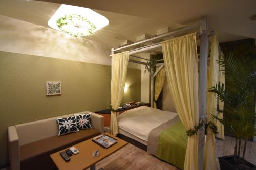 a bedroom with a bed and a couch and a table at Hotel Melia RESORT(Adult Only) in Fuefuki